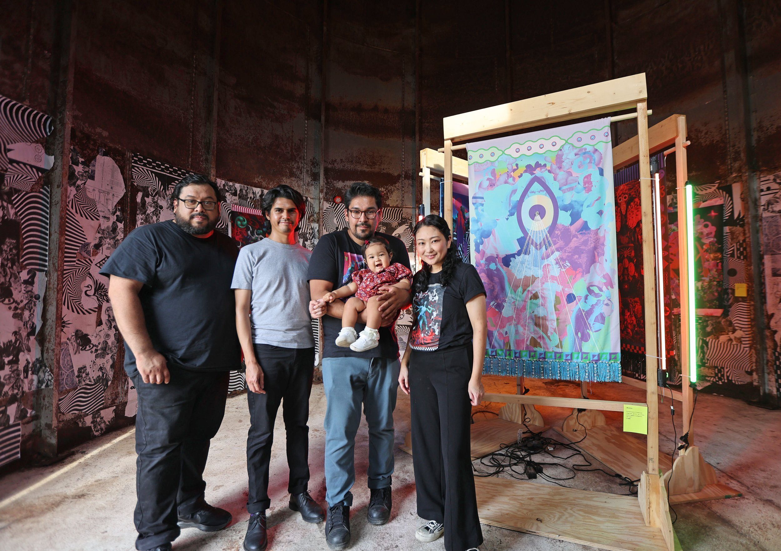 The Essentials Creative collective standing together in front of a backlit tapestry installation