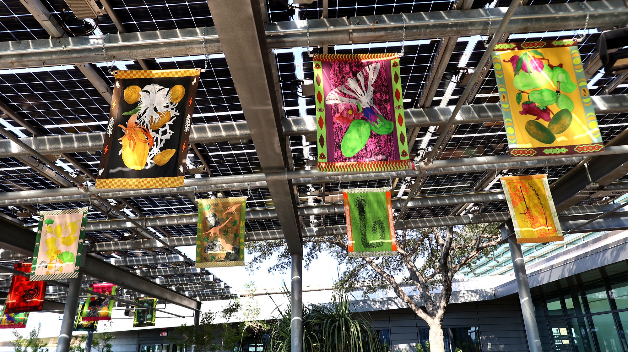 Multiple tapestries suspended beneath solar panels