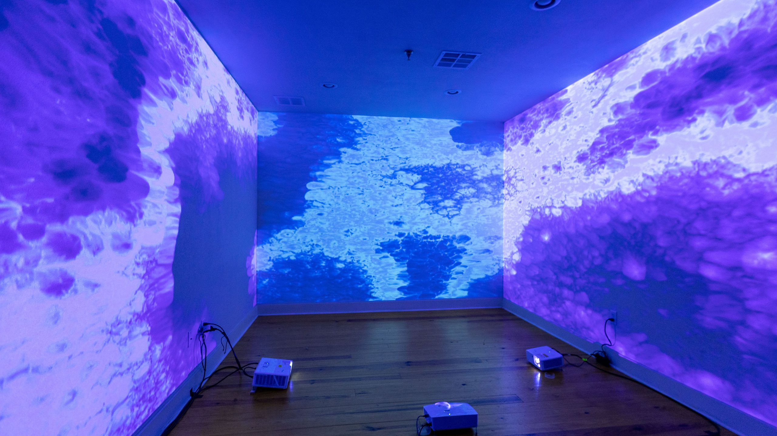 Empty room saturated in violet and blue water-pattern projections