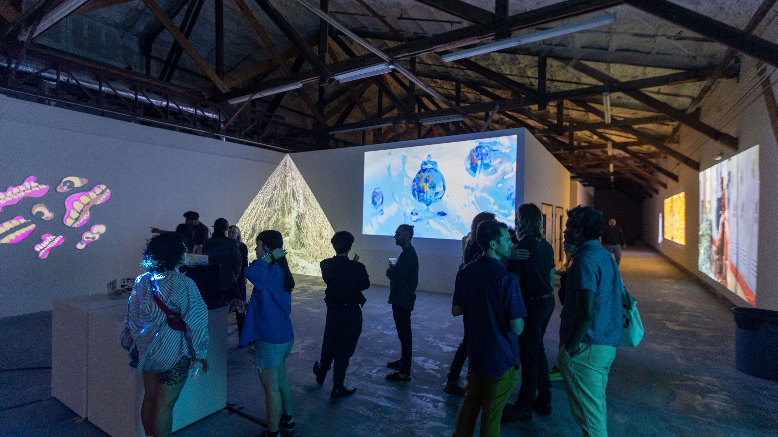 Crowd around paper pyramid sculpture with blue-sphere screen behind